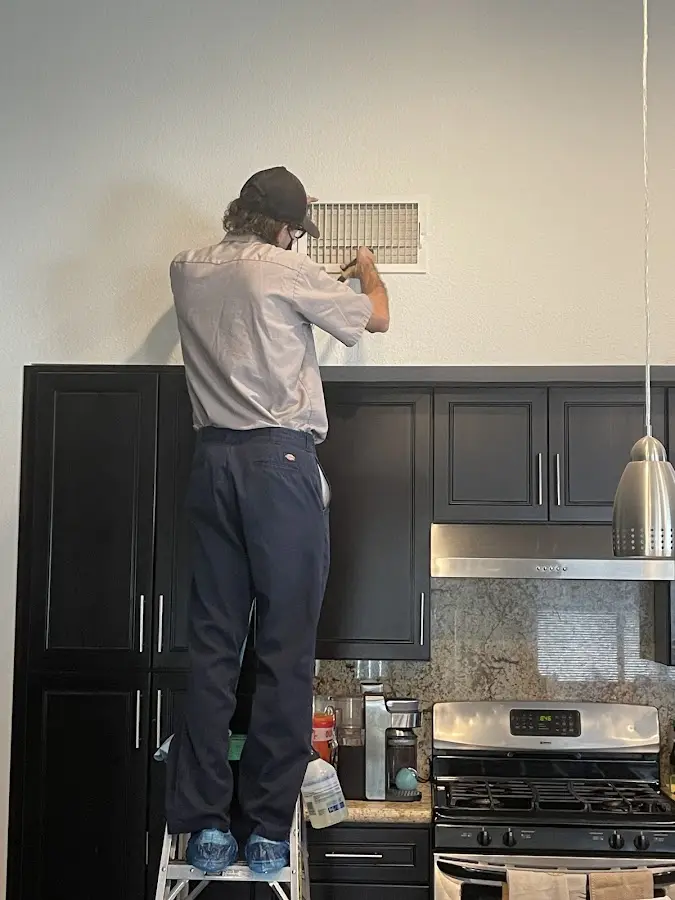 Technician inspecting an air vent during HVAC service in Easley